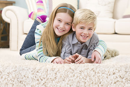 Children smiling while laying on fresh clean carpet