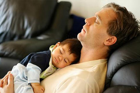 Father and child sleeping on leather chair