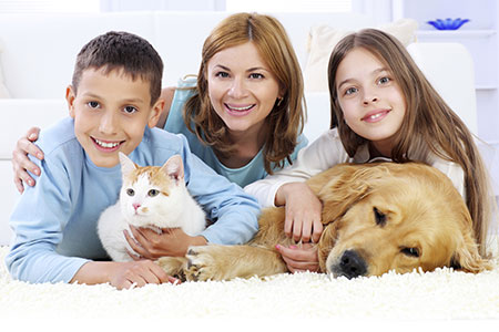 Mother and children laying on carpet with pets